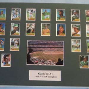 Può includere: Un collage incorniciato di carte da baseball con giocatori degli Oakland A's della squadra campione della World Series del 1989. Le carte sono disposte in una griglia e mostrano diversi giocatori con le loro uniformi. La cornice è nera e ha un passepartout bianco. Il titolo "Oakland A's 1989 World Champions" è stampato sotto le carte.