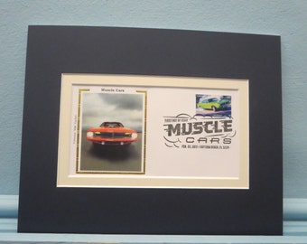 May include: A framed image of a red 1971 Plymouth Cuda muscle car with the text "First Day of Issue Muscle Cars Feb. 22, 2013 Daytona Beach, FL 32119" printed below.