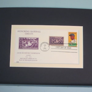 May include: A framed display honoring baseball great Jackie Robinson. The display includes stamps and text that reads "Honoring Baseball Greats" and "First Day of Issue". The stamps feature images of baseball players and a portrait of Jackie Robinson.