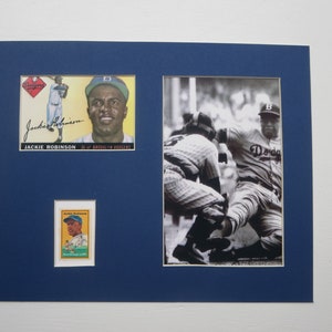 May include: A framed photo of Jackie Robinson, a famous baseball player. The photo includes two baseball cards of Robinson, one in color and one in black and white. The photo shows Robinson sliding into home plate.