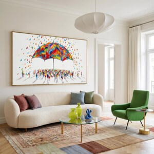 May include: A large rectangular wall art piece featuring a vibrant, multi-colored umbrella sheltering a crowd of small, abstract figures. The scene is set against a white background with colorful, scattered raindrops falling around the umbrella.