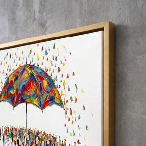 May include: A framed canvas painting featuring a large, multi-colored umbrella with thick, textured impasto paint strokes. Below the umbrella, a crowd of small, colorful figures stands on a white background, with vibrant rain droplets falling.