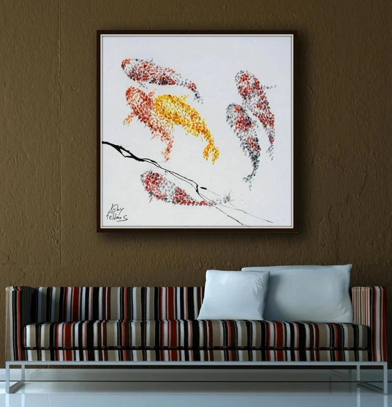 May include: An abstract painting of koi fish in shades of red, yellow, and black on a white background, framed in a dark wood. The artwork hangs above a striped sofa with white pillows.