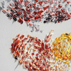 May include: Close-up of an abstract painting on a white canvas. The artwork features textured brushstrokes in shades of red, orange, yellow, silver, and black. The painting's composition is suggestive of a heart shape.