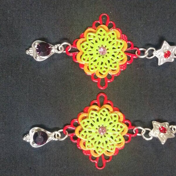 A pair of silver dangle earrings with red, orange and lime green metal like doilies