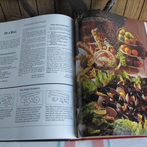 Puede incluir: Libro de cocina abierto con una receta para "On a Roll" de rollos de mantequilla en forma de media luna y una foto de un plato de mariscos con almejas, mejillones y rodajas de lim&oacute;n. El libro de cocina est&aacute; abierto en la secci&oacute;n "Cenas festivas".