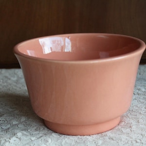 May include: A large, peach-colored ceramic planter with a rounded bottom and a wide, flared rim.