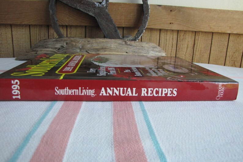 Puede incluir: Un libro de cocina de tapa dura roja titulado "Southern Living Annual Recipes 1995" con el texto "Southern Living Annual Recipes" en el lomo.
