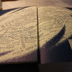 May include: A detailed map of the Star Wars galaxy, showing the Corellian Trade Spine, the Outer Rim, and the Hutt Space region. The map is printed on a book page with a blue background and white stars.