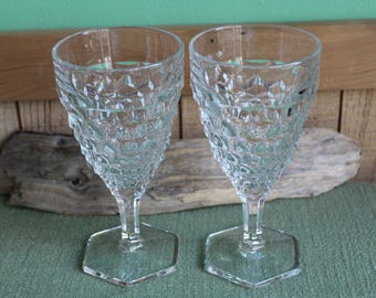 May include: Two clear glass wine glasses with a textured, diamond-shaped pattern. The glasses have a hexagonal base.