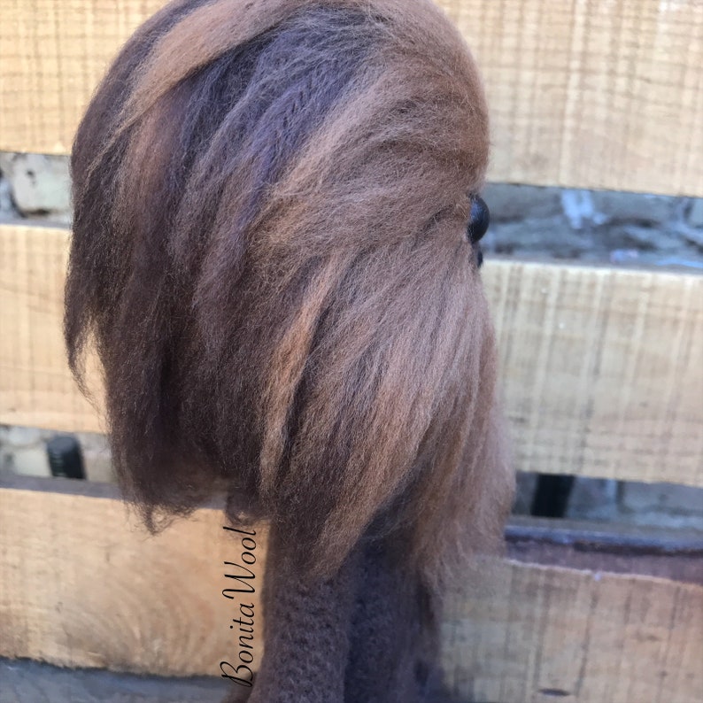K&ouml;nnte beinhalten: Eine braune und schwarze Filz-Chewbacca-Puppe mit einem schwarzen Auge. Die Puppe steht auf einer Holzoberfl&auml;che. Der Text "Bonita Wool" ist auf dem K&ouml;rper der Puppe sichtbar.