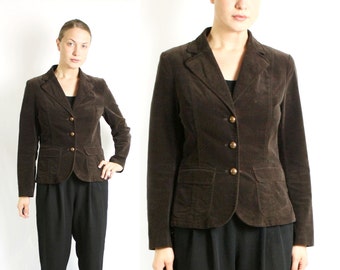 Op de afbeelding: Een bruine corduroy blazer met knoopsluiting en twee voorzakken. De blazer is getailleerd en heeft een klassieke stijl.