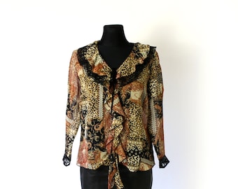 May include: A long-sleeved blouse with a ruffled neckline and a paisley and leopard print pattern. The blouse is made of a sheer fabric and has a black lace trim.