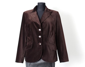 Op de afbeelding: Een bruin fluwelen blazer met knoopsluiting en een zwarte leren rok.