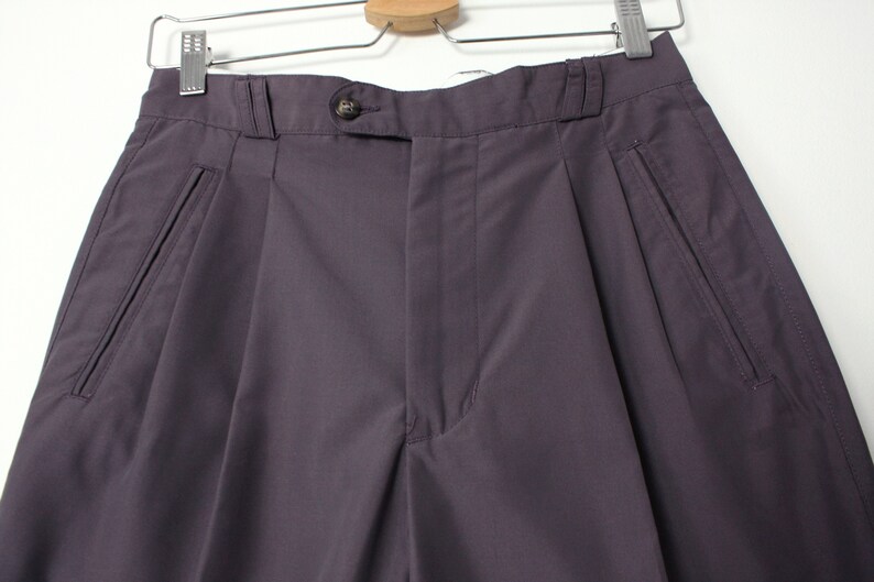 Puede incluir: Un pantal&oacute;n gris oscuro con pliegues y bolsillos delanteros.