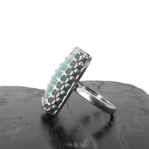 May include: A silver ring with a green gemstone set in a decorative floral design.