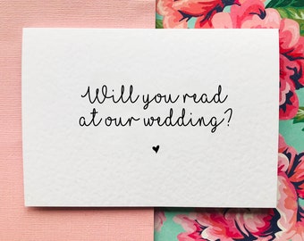 Könnte beinhalten: Weiße Karte mit schwarzem Text, der "Willst du bei unserer Hochzeit lesen?" lautet, mit einem kleinen schwarzen Herz unter dem Text.