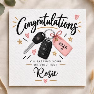 Peut inclure: Une carte de vœux carrée avec le texte Congratulations on passing your driving test Rosie. Le design présente une illustration d'une clé de voiture noire et d'une étiquette rectangulaire rose avec l'année 2026, décorée de cœurs et d'étoiles.