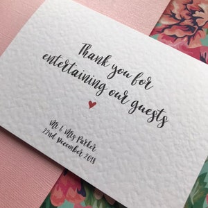 May include: White card with black calligraphy that reads "Thank you for entertaining our guests" with a small red heart. Below the text is "Mr & Mrs Parker 22nd December 2018".