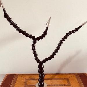 May include: A black flexible gooseneck desk lamp with three adjustable arms and clips. The lamp has a silver base and is on a brown surface.