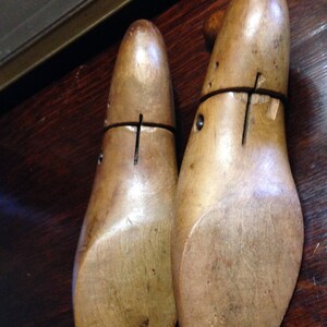 May include: Two wooden shoe stretchers, also known as shoe trees, are made of light brown wood. The stretchers are designed to help maintain the shape of shoes and prevent wrinkles.