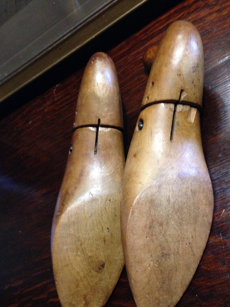 May include: Two wooden shoe stretchers, also known as shoe trees, are made of light brown wood. The stretchers are designed to help maintain the shape of shoes and prevent wrinkles.