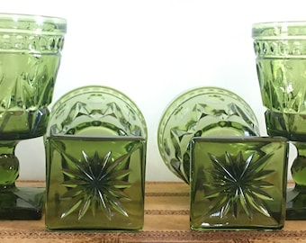 May include: Set of four green glass goblets with a square base and a starburst pattern. The goblets are made of clear glass with a green tint.