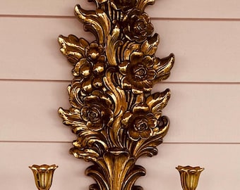 Pode incluir: Aplique de parede dourado com dois castiçais e um design floral.