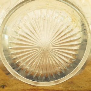 May include: Close-up of the bottom of a clear glass pitcher with a starburst pattern.