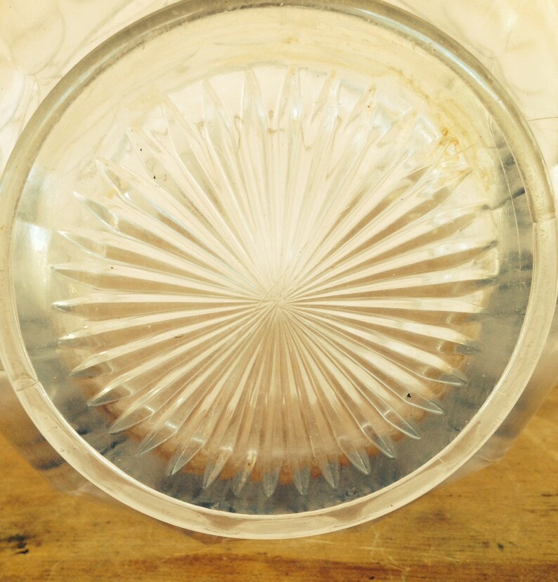 May include: Close-up of the bottom of a clear glass pitcher with a starburst pattern.