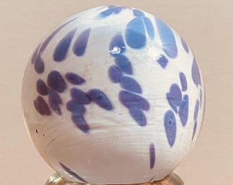 May include: White glass marble with a blue and white swirl pattern.