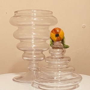 Peut inclure: Un pot en verre transparent avec un design en couches et un couvercle décoratif représentant un fruit jaune et orange avec des feuilles vertes.
