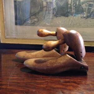 May include: Two wooden shoe trees with a brown finish. The shoe trees have a rounded shape and are designed to help maintain the shape of shoes.
