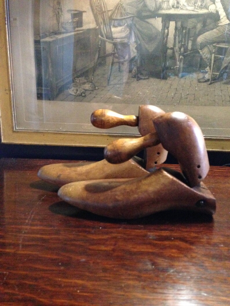 May include: Two wooden shoe trees with a brown finish. The shoe trees have a rounded shape and are designed to help maintain the shape of shoes.