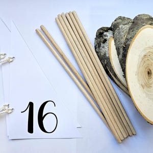 May include: White triangle pennant with the number 16 printed in black. The pennant has two white strings attached to the top corners. A bundle of wooden dowels and three wooden slices are also in the image.
