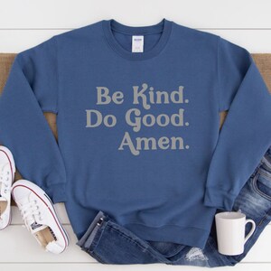 May include: A blue sweatshirt with the text "Be Kind. Do Good. Amen." in a light gray color.
