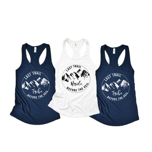 May include: Three tank tops with a mountain range graphic and the text "Last Trail" and either "Bride" or "Tribe" with the words "Before the Veil".