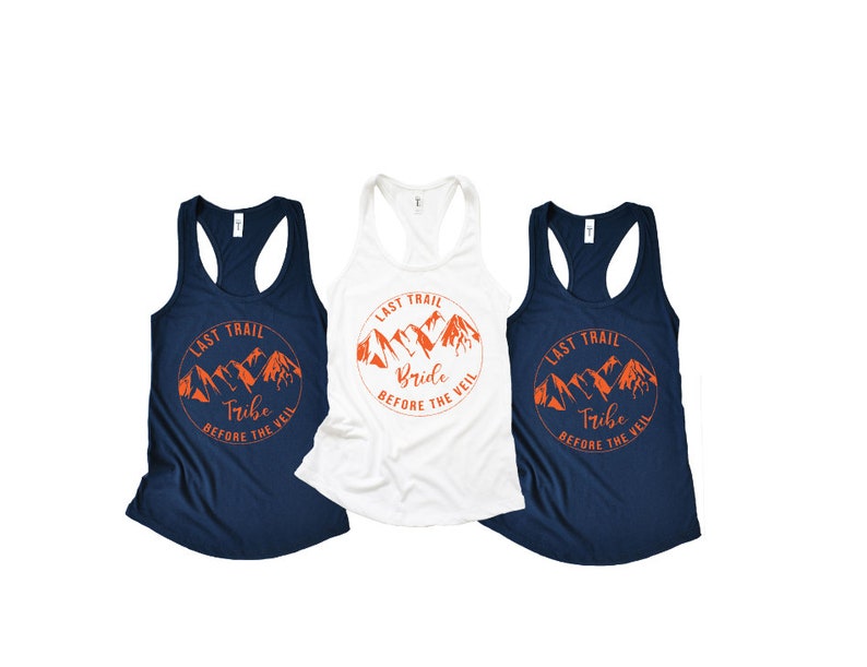 May include: Three tank tops with a mountain range graphic and the text "Last Trail" in a circle. The top on the left says "Tribe" and the top in the middle says "Bride". The top on the right says "Tribe".