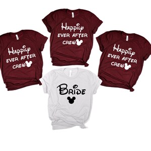 K&ouml;nnte beinhalten: Vier T-Shirts mit Disney-Motiv. Drei weinrote T-Shirts mit wei&szlig;em Text, der "Happily Ever After Crew" lautet, und einem wei&szlig;en Mickey-Maus-Kopf. Ein wei&szlig;es T-Shirt mit schwarzem Text, der "Bride" lautet, und einem schwarzen Mickey-Maus-Kopf.