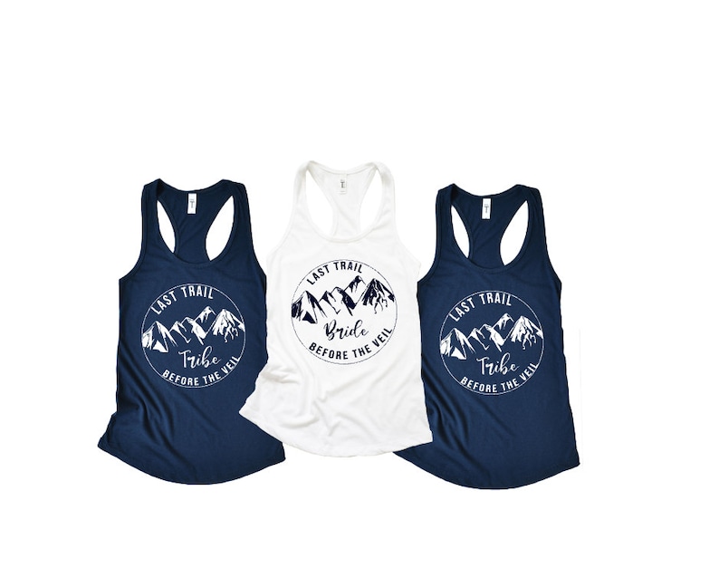 May include: Three white tank tops with a navy blue mountain graphic and the text "Last Trail" and either "Bride", "Tribe", or "Tribe" printed on the front.