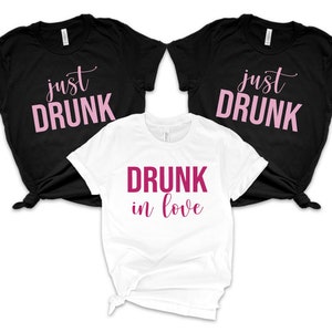 May include: Three t-shirts with the text "just drunk" in pink on black shirts and "drunk in love" in pink on a white shirt.