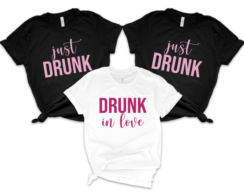 May include: Three t-shirts with the text "just drunk" in pink on black shirts and "drunk in love" in pink on a white shirt.