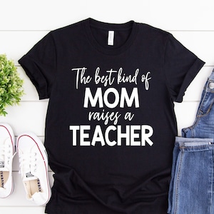 Puede incluir: Camiseta negra con texto blanco que dice "The best kind of MOM raises a TEACHER".