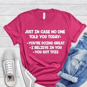 May include: A pink t-shirt with the text "JUST IN CASE NO ONE TOLD YOU TODAY: -YOU'RE DOING GREAT -I BELIEVE IN YOU -YOU GOT THIS" in white.