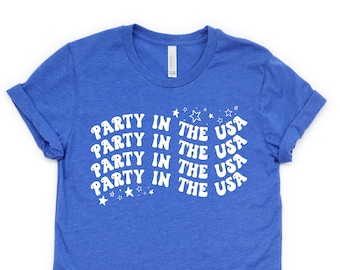 May include: A royal blue t-shirt with a white graphic that says "PARTY IN THE USA" repeated four times. The graphic is in a retro font with stars around it.