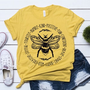 May include: A yellow t-shirt with a black bee graphic and the text "Happy, Smart, Brave, Confident, Fun, Positive, Kind, Humble, Creative, Joyful, Yourself".