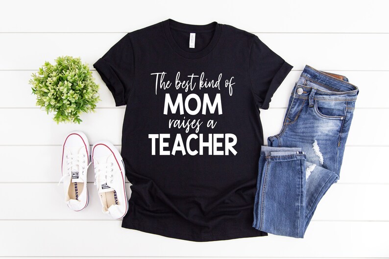 Puede incluir: Camiseta negra con texto blanco que dice "The best kind of MOM raises a TEACHER".