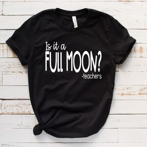 May include: Black t-shirt with white text that reads "Is it a FULL MOON? -teachers"