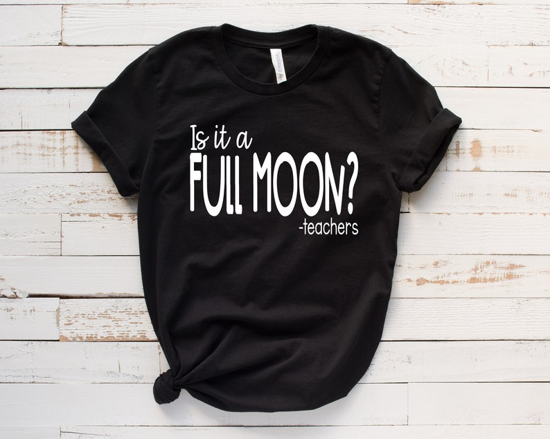 May include: Black t-shirt with white text that reads "Is it a FULL MOON? -teachers"