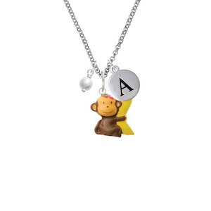 May include: Silver necklace with a monkey charm holding a banana, a pearl bead, and a silver charm with the letter A.